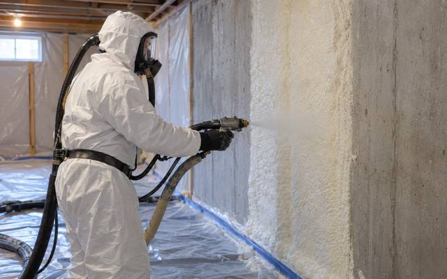 Installer spraying foam onto a basement foundation wall in Waterloo