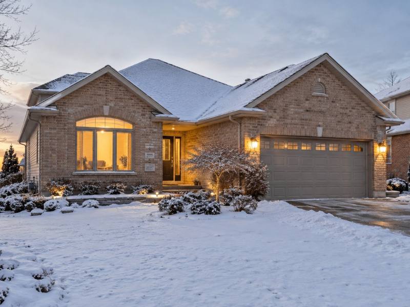 Two-story brick home with snow on the lawn at dusk
